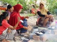Local women in Bukit Lawang prepare a traditional Indonesian meal over an open fire, showcasing authentic village fire. 