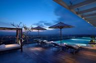 Infinity pool at Marriott Hotel Medan with city lights in the distance, captured during evening twilight. 
