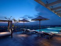 Infinity pool at Marriott Hotel Medan with city lights in the distance, captured during evening twilight. 