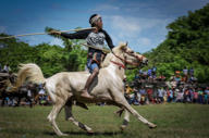 Sumba warrior in traditional attire charging on horseback during the Pasola Festival, a ceremonial spear-throwing event in Indonesia. 