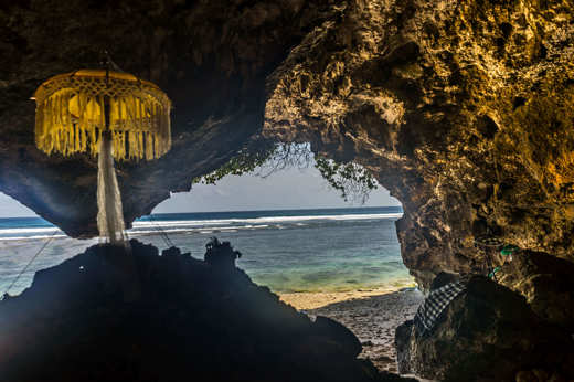 A traditional Balinese shrine stands in seaside cave, facing the ocean at a sacred coastal temple in Bali, Indonesia. 