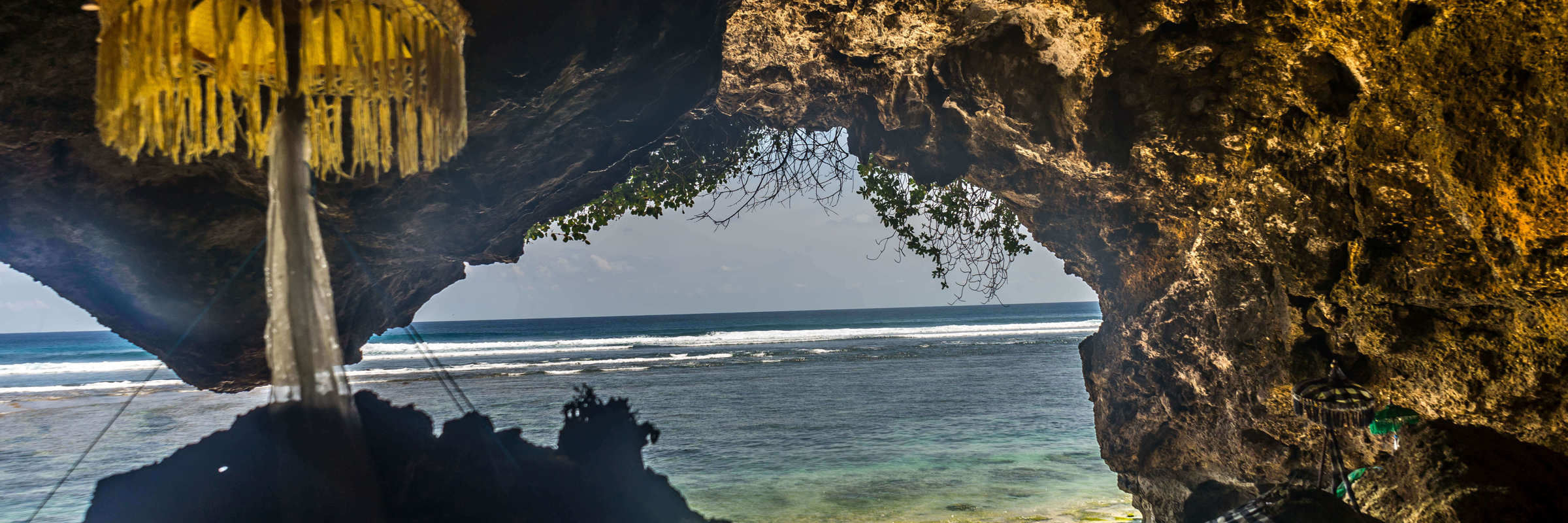 A traditional Balinese shrine stands in seaside cave, facing the ocean at a sacred coastal temple in Bali, Indonesia. 