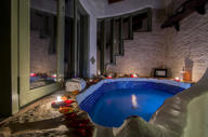 Romantic indoor bathtub at El Guarumo Lodge, lit with candles and surrounded by natural stone. 