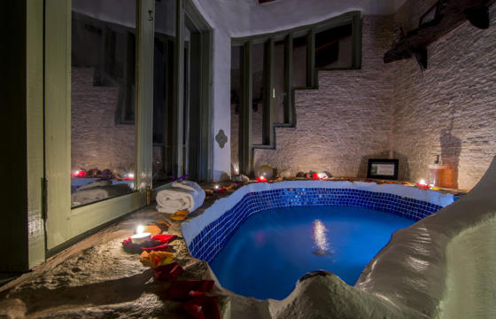 Romantic indoor bathtub at El Guarumo Lodge, lit with candles and surrounded by natural stone. 