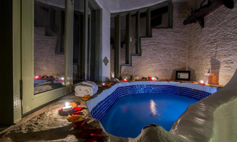 Romantic indoor bathtub at El Guarumo Lodge, lit with candles and surrounded by natural stone. 