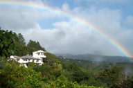 Rainbow arcs over the lush hills and white villa of Finca Rosa Blanca in Costa Rica. 