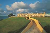 The fortified walls of Campeche at sunset, with a yellow walkway leading toward the sea and colonial ramparts. 