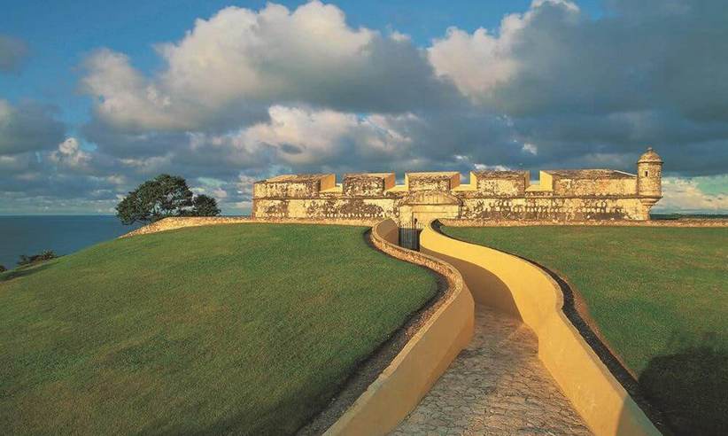 The fortified walls of Campeche at sunset, with a yellow walkway leading toward the sea and colonial ramparts. 