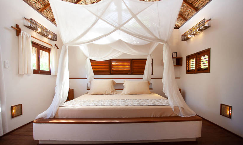Rustic eco-lodge bedroom in Brazil with canopy bed, wooden ceiling, and soft natural lighting. 