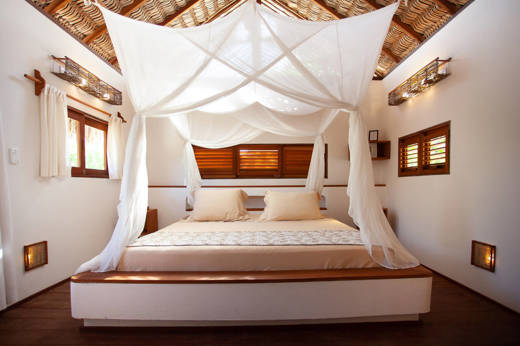 Rustic eco-lodge bedroom in Brazil with canopy bed, wooden ceiling, and soft natural lighting. 