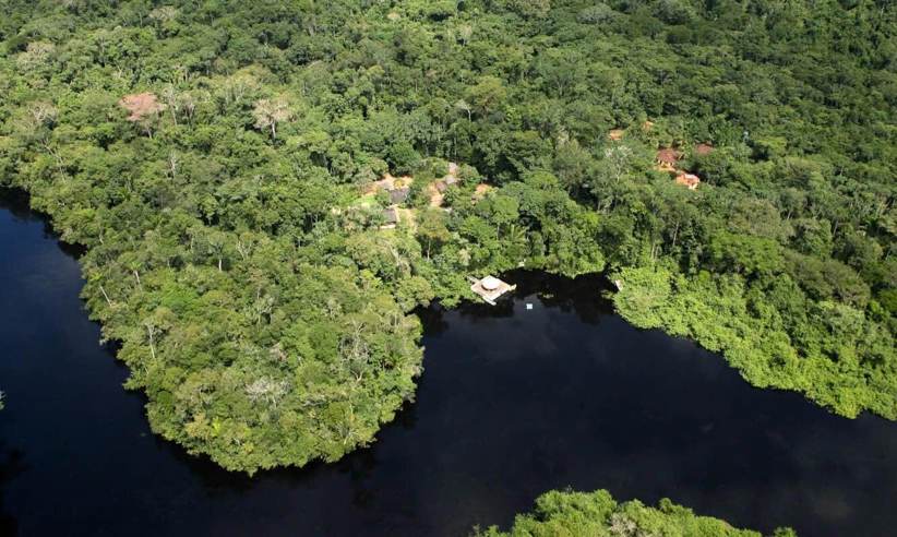 Aerial view of Cristalino Jungle Lodge surrounded by dense Amazon rainforest and winding blackwater river in Brazil. 