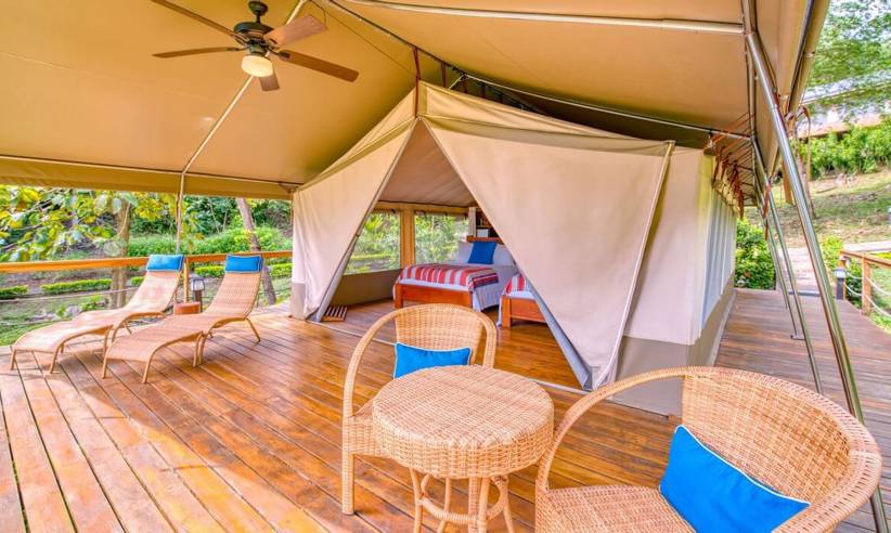 A spacious glamping tent with cozy furnishings and wooden deck invites relaxation amid the natural beauty of Costa Rica. 