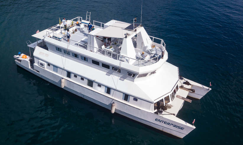 Aerial view of the Enterprise catamaran cruising the waters off Brazil, showcasing its modern design and spacious deck. 
