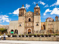 Santo Domingo Church in Oaxaca, Mexico, with its twin bell towers and historic Baroque facade under a blue sky. 