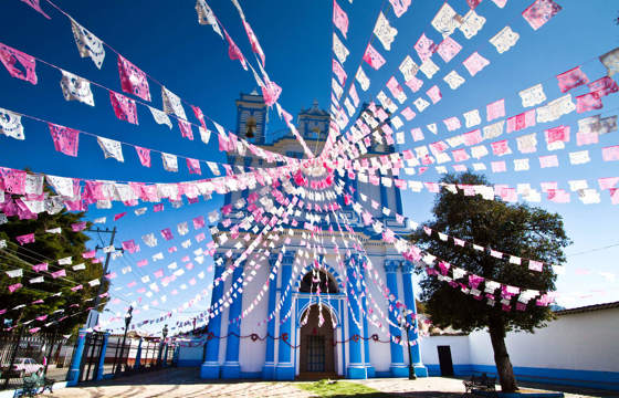 Colourful church in San Cristobal de las Casas decorated with vibrant papel picado banners in Chiapas, Mexico 