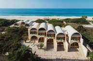 Aerial view of Hotel Escondido, a luxury beachfront eco-hotel with white arched villas on the Oaxaca coast in Mexico. 