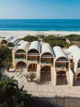 Aerial view of Hotel Escondido, a luxury beachfront eco-hotel with white arched villas on the Oaxaca coast in Mexico. 