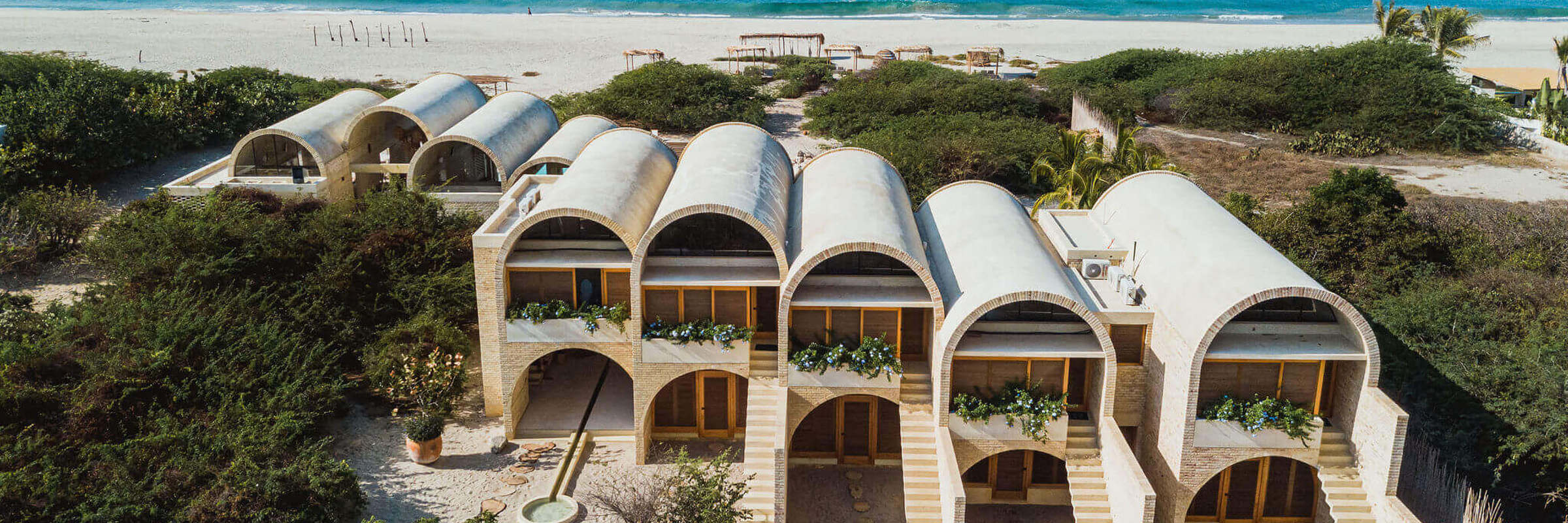 Aerial view of Hotel Escondido, a luxury beachfront eco-hotel with white arched villas on the Oaxaca coast in Mexico. 