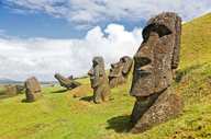 Iconic Moai statues of Easter Island stand on grassy hills under a dramatic sky at Rano Raraku quarry. 