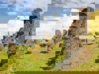 Iconic Moai statues of Easter Island stand on grassy hills under a dramatic sky at Rano Raraku quarry. 