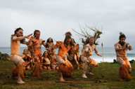 Traditional Rapa Nui dancers in costume perform on Easter Island with ocean backdrop and cultural heritage on display. 