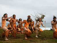 Traditional Rapa Nui dancers in costume perform on Easter Island with ocean backdrop and cultural heritage on display. 