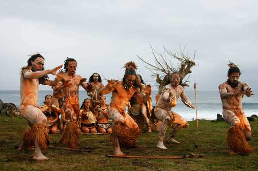 Traditional Rapa Nui dancers in costume perform on Easter Island with ocean backdrop and cultural heritage on display. 