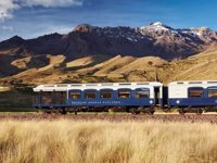 The Belmond Andean Explorer train crossing the high plans of Peru with the Andes in the background. 