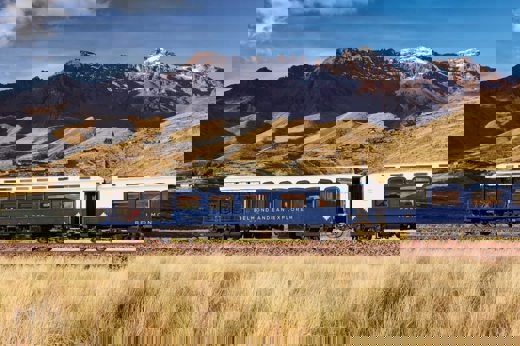 The Belmond Andean Explorer train crossing the high plans of Peru with the Andes in the background. 