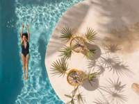 Overhead view of the swimming pool at Casa Sandra on Holbox Island, with tropical plants and a guest swimming below. 