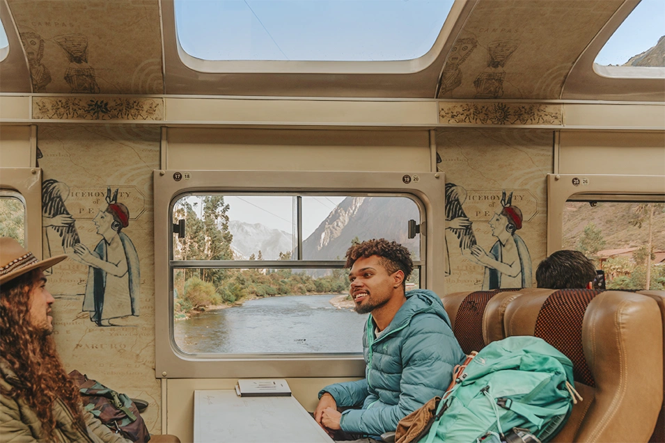 Travellers enjoying the view through panoramic windows aboard train to Machu Picchu. 