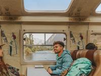 Travellers enjoying the view through panoramic windows aboard train to Machu Picchu. 