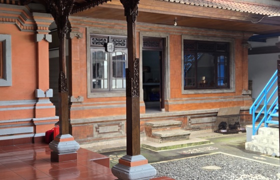 A traditional Balinese home with carved wooden columns and an open courtyard, showcasing local architect details. 