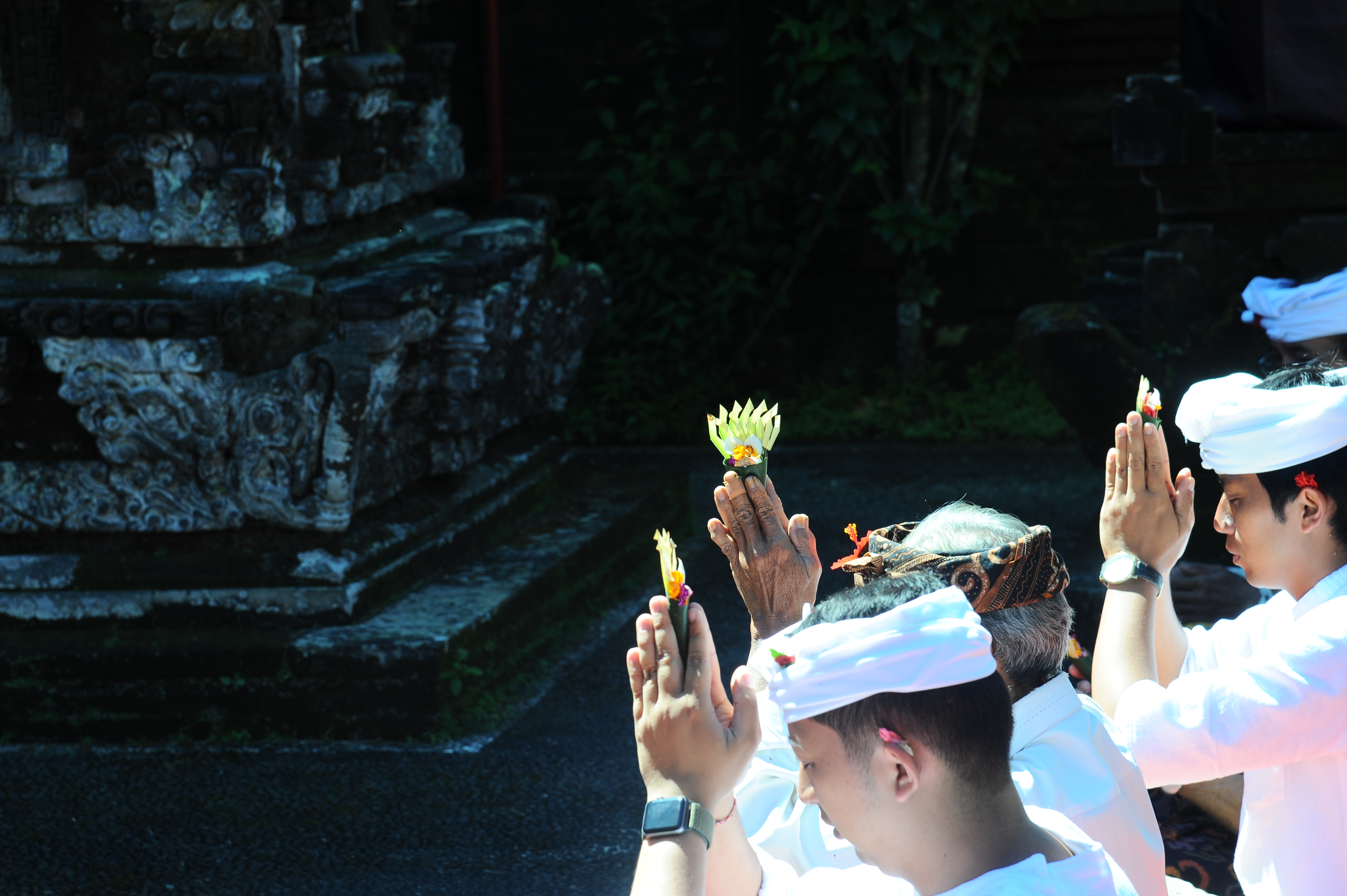 Balinese men in ceremonial dress raise offerings during a Hindu prayer ritual at a temple in Bali, Indonesia. 