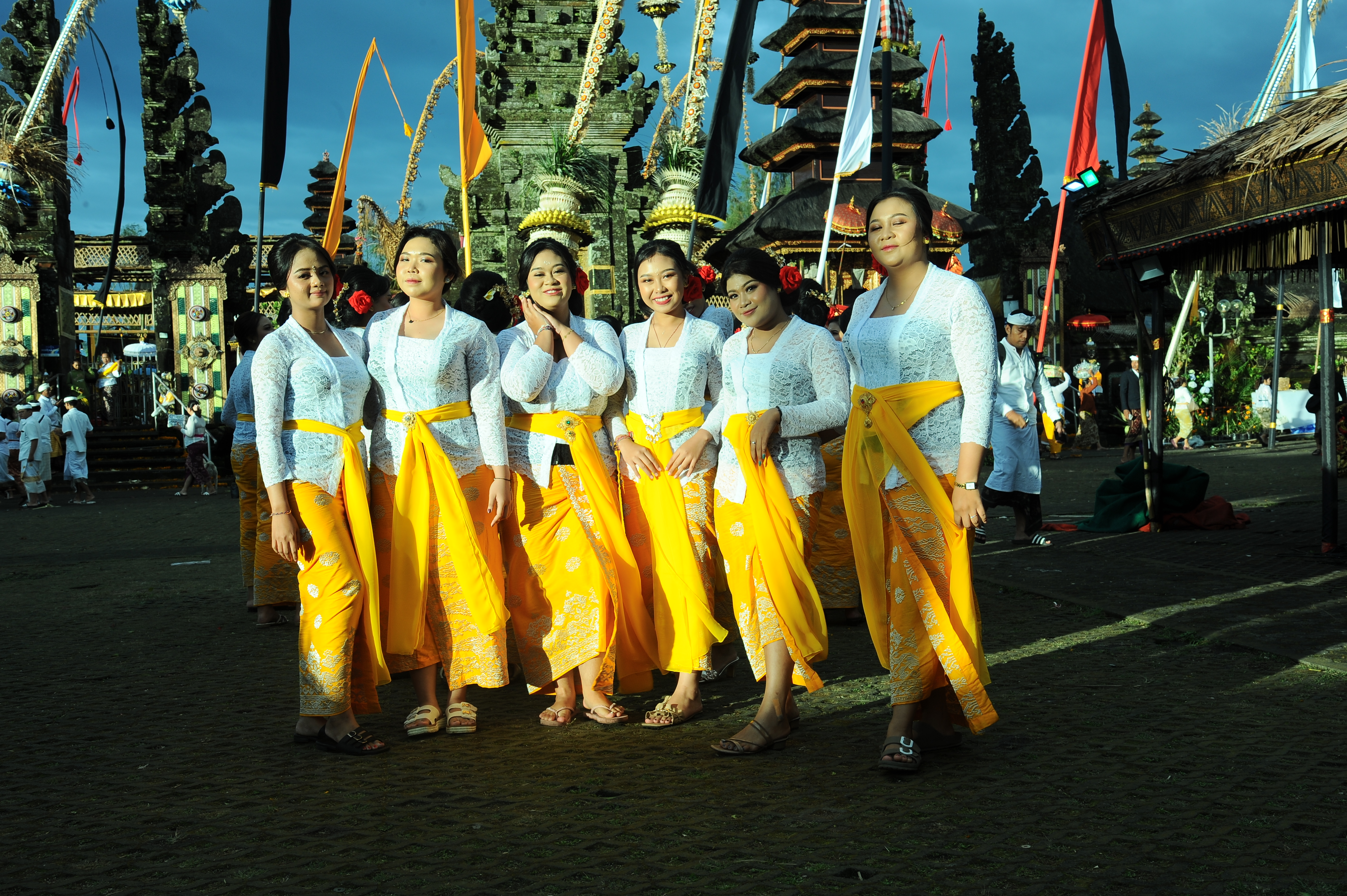 Balinese women in white kebaya and golden sarongs pose during the Galungan festival in Bali, Indonesia. 