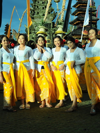 Balinese women in white kebaya and golden sarongs pose during the Galungan festival in Bali, Indonesia. 
