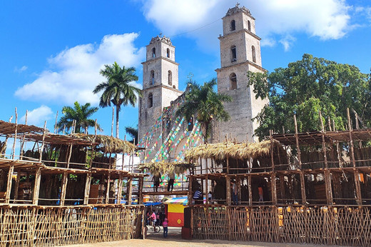 Traditional wooden setup for the Espita Yucatan Feria with the colonial church and palm trees in the background. 