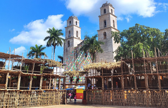 Traditional wooden setup for the Espita Yucatan Feria with the colonial church and palm trees in the background. 