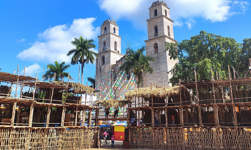 Traditional wooden setup for the Espita Yucatan Feria with the colonial church and palm trees in the background. 