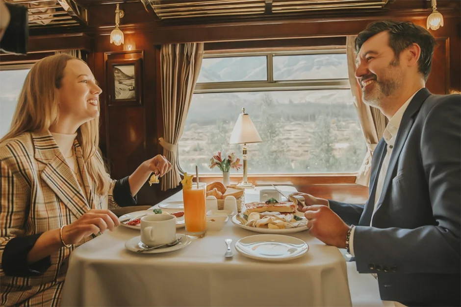 A couple enjoys luxurious breakfast in the elegant dining carriage of the PeruRail Titicaca Train. 