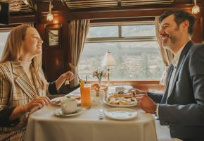 A couple enjoys luxurious breakfast in the elegant dining carriage of the PeruRail Titicaca Train. 