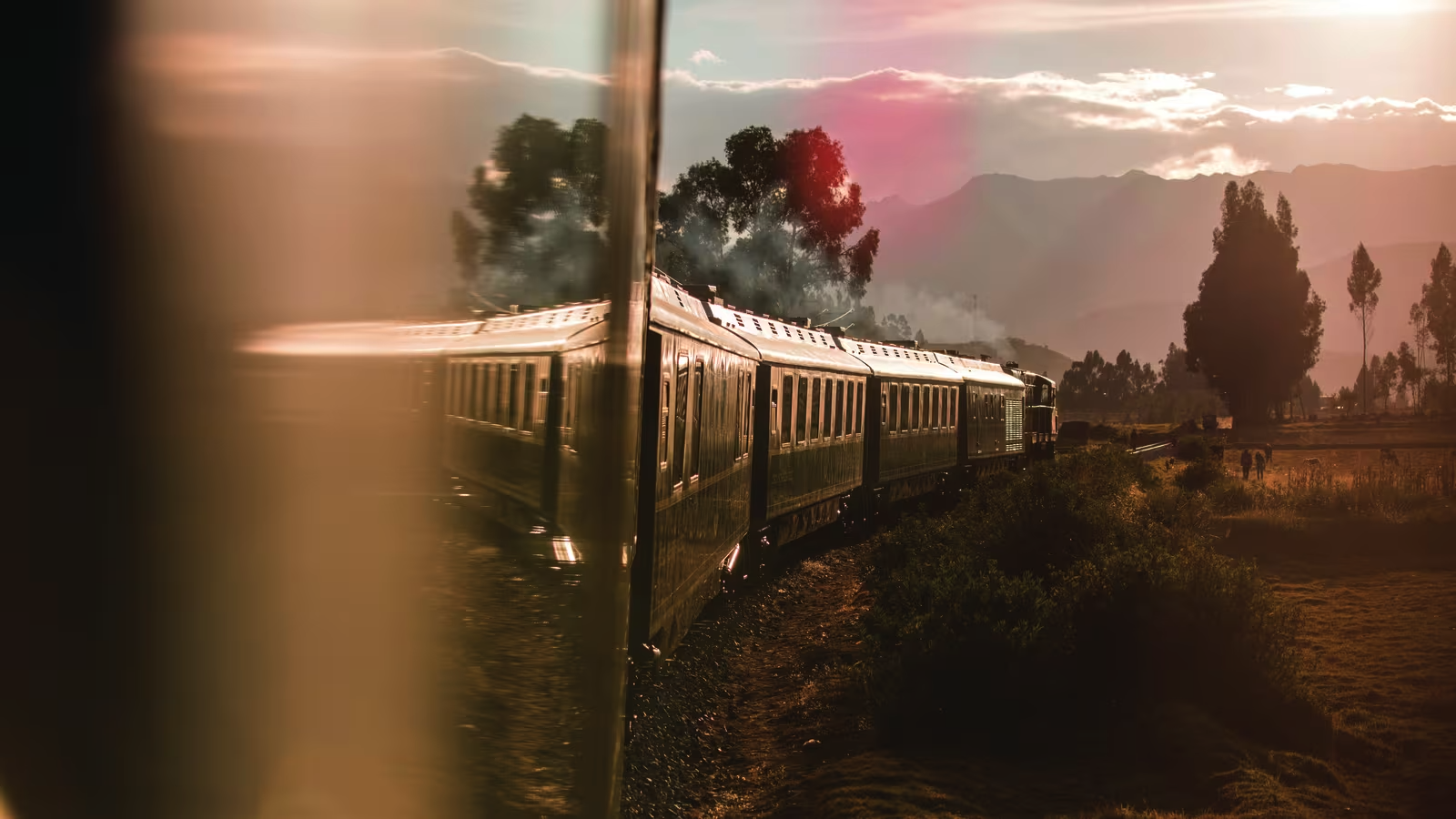 Luxury train journey to Machu Picchu passing through scenic countryside at sunset. 