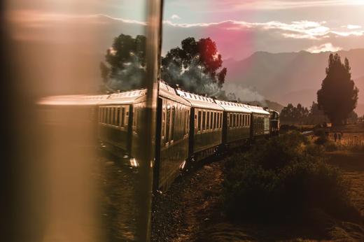 Luxury train journey to Machu Picchu passing through scenic countryside at sunset. 