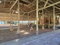 Children playing badminton inside a traditional wooden pavilion with high thatched roof in Bali, Indonesia. 